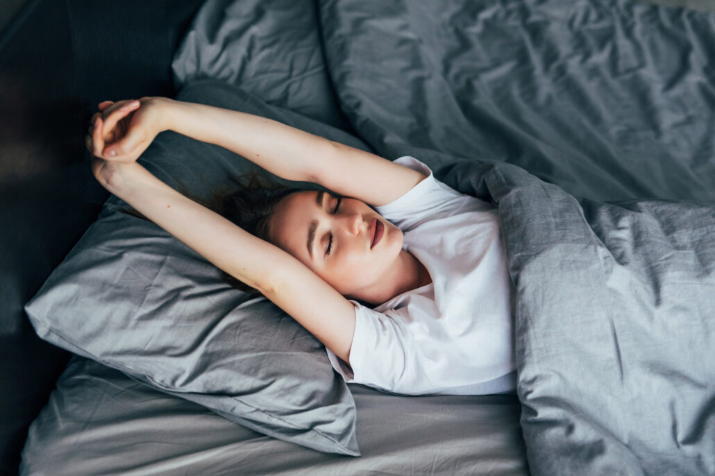 Girl stretching in bed after waking up.