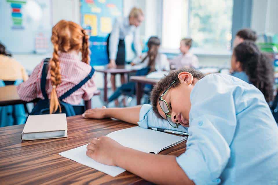 overworked african american schoolboy sleeping in class