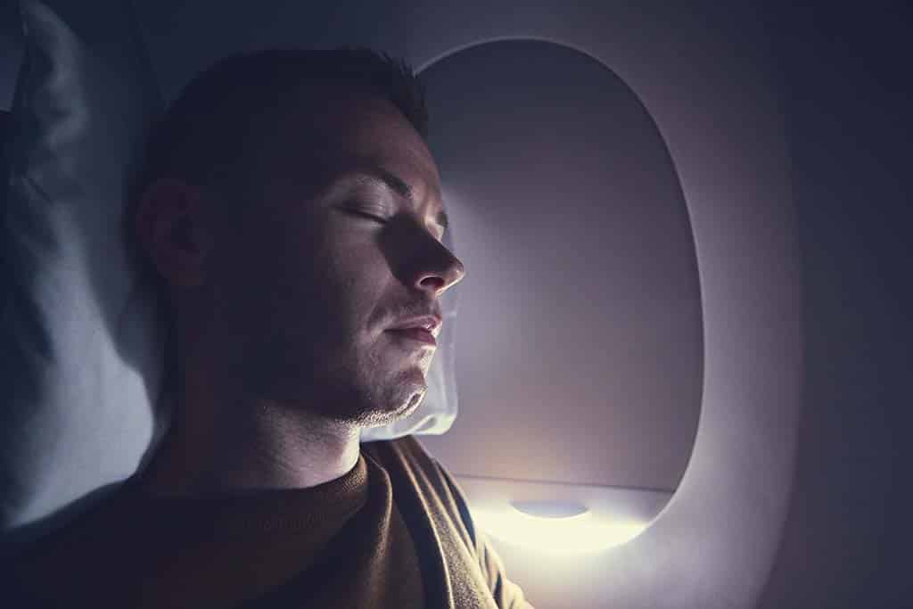 Traveling by airplane. Young passenger sleeping during flight.